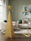 Golden glitter Christmas tree adorned with lights, set in a stylish living room with modern furniture and decor.