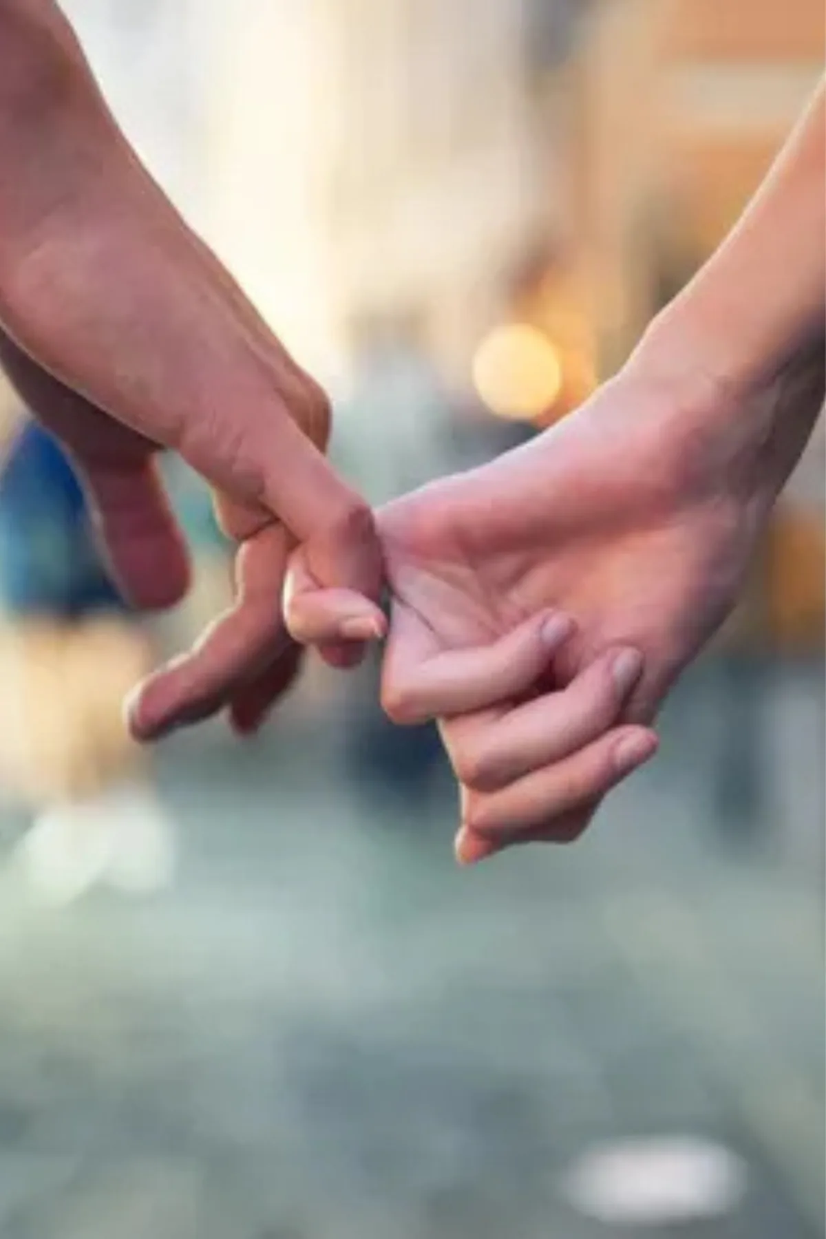 Two hands intertwined while walking together, symbolizing unity and connection in a romantic setting.